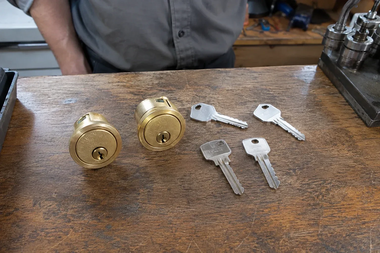 Two detached brass lock cylinders and four house keys on a wooden counter. — Lock Rekeying, Pickering